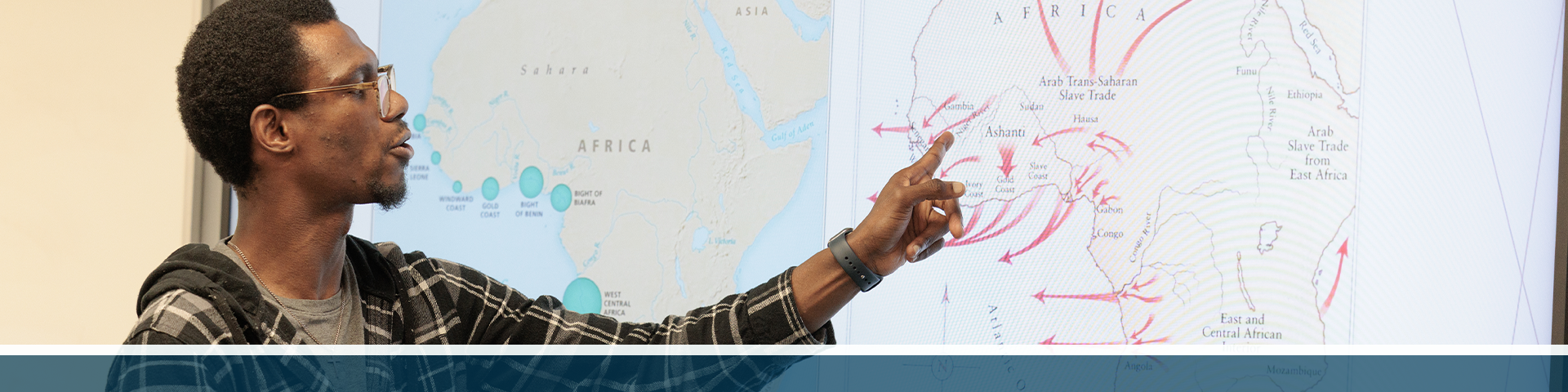 A professor in front of a classroom gesturing to a diagram about the Atlantic Slave Trade